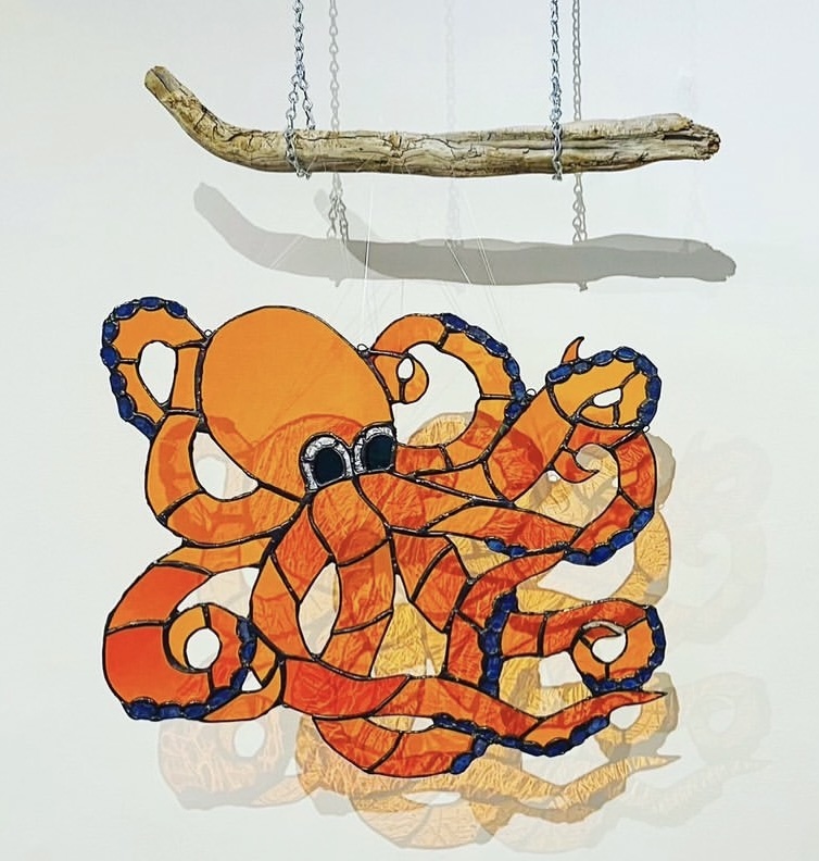 orange stained-glass octopus hanging from a piece of driftwood