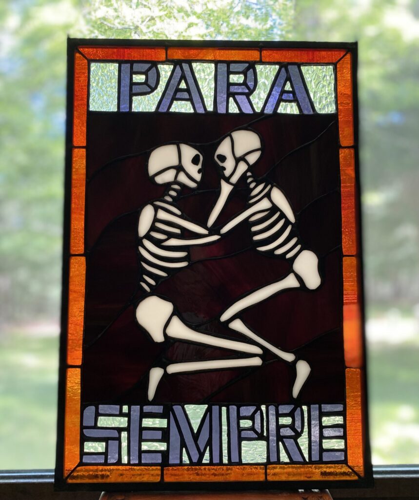 stained glass window of two skeletons embracing, surrounded by the words "Para Sempre"